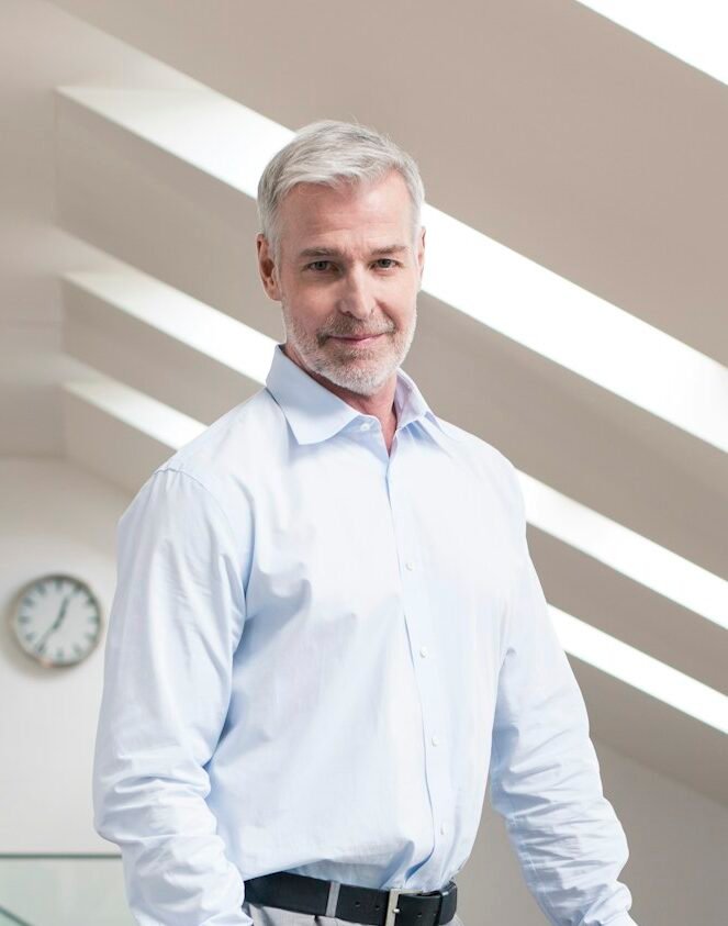 Serene businessman standing at railing in his office